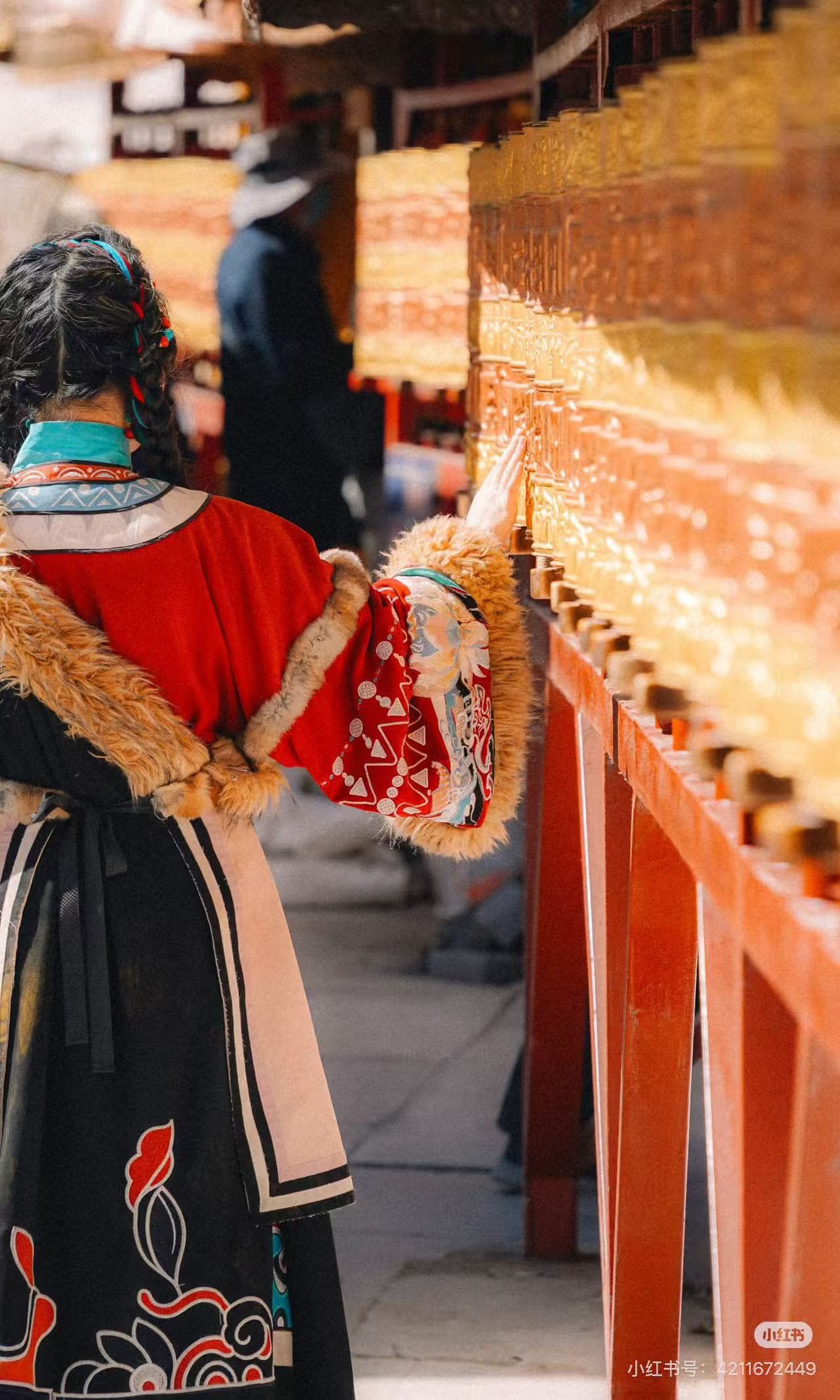 Vibrant traditional attire on person spinning golden prayer wheels, rich cultural experience in Tibet - ChinaTripTop.